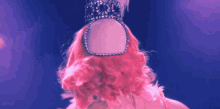 a woman with pink hair is wearing a tiara on her head