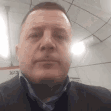 a man in a suit and tie is looking at the camera in a subway station .