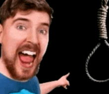 a man with a beard is pointing at a noose with his tongue out .