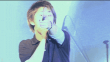 a man in a black shirt is singing into a microphone and making a funny face
