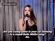 a woman is singing into a microphone while standing on a stage .