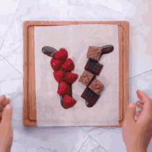 a wooden cutting board with strawberries chocolate and m&m 's on it
