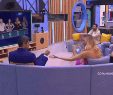a group of people are sitting on a couch in a living room watching a television .