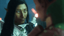 a woman with long black hair and green eyes looks at another woman