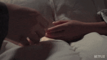 a person laying in bed holding another person 's hand with a netflix logo in the background