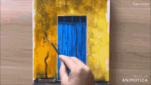a person is painting a blue door on a yellow building