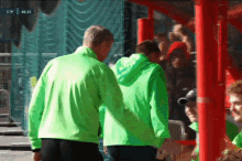 two men in green jackets are walking in front of a screen that says ctp at the top