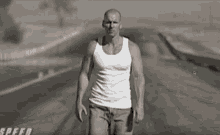 a man in a white tank top walks down a road with the word speed below him