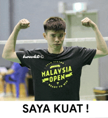 a man wearing a malaysia open t-shirt flexes his arms