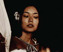 a woman with a flower in her hair is looking down at something .