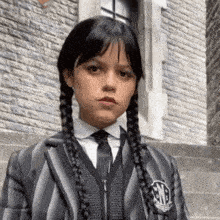 a girl wearing a striped jacket and tie has braids in her hair