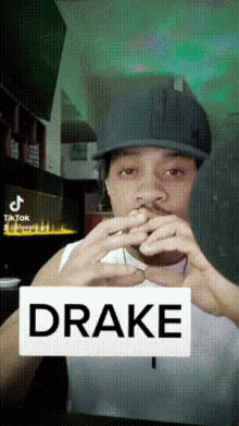 a man wearing a hat is making a heart with his hands and the word drake is on the screen