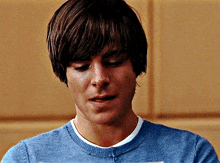 a close up of a man 's face with a blue shirt on