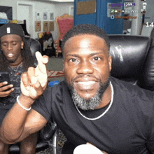 a man with a beard is sitting in a chair giving the middle finger