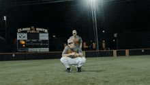 two baseball players squatting in front of a scoreboard that says claude smith field