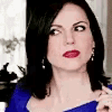 a close up of a woman 's face wearing a blue shirt and earrings .