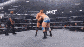 two men are wrestling in a ring with nxt written on the bottom