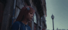 a woman with red hair is walking down a city street