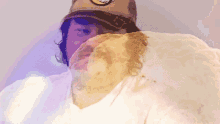 a man wearing a hat and a white shirt has a huge amount of food on his face