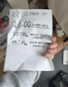 a person is holding a piece of paper that says " 22:00 " on it