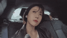 a woman sitting in the back seat of a car with korean writing on the bottom right