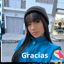 a woman wearing a beanie and a blue jacket with the words gracias in the corner