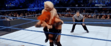 two women are wrestling in a wrestling ring with a referee watching