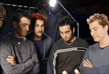 a group of men are standing together with their arms crossed and one has a necklace around his neck