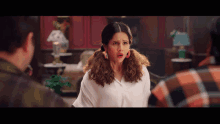 a woman with a surprised look on her face is talking to two men