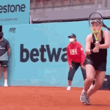 a woman is holding a tennis racquet on a tennis court in front of an advertisement for betwa .