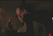 a man in a dark room with a red triangle behind him