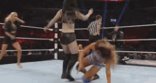 a group of women are wrestling in a ring with a referee watching .