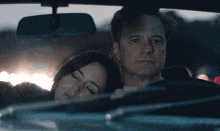 a man is driving a car with a woman sleeping on his lap