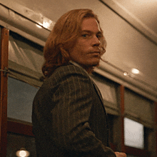 a man with long hair wearing a striped suit
