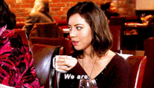 a woman is sitting at a table with a cup of coffee and a glass of wine and says we are