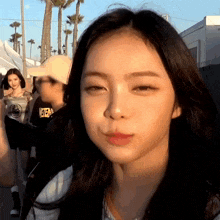a girl with long black hair is making a funny face while wearing a yellow hat .