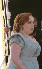 a woman with red hair is wearing a blue dress