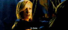 a woman with blonde hair is talking to a man in a dark room and says hi daddy .