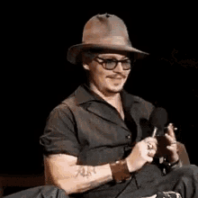 a man in a cowboy hat is sitting in a chair smoking a cigarette .
