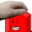 a hand is putting a towel on top of a red block with a face .
