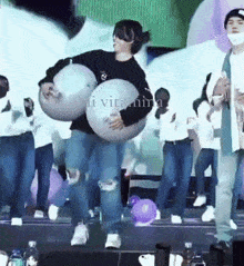 a group of people are dancing on a stage and one of them is carrying a balloon .