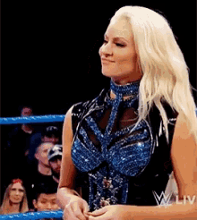 a woman is standing in a wrestling ring with a crowd watching .