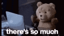 a teddy bear is sitting in front of a laptop computer with the words `` there 's so much '' written on it .