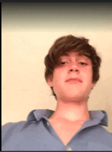 a young man wearing a blue shirt is taking a selfie .