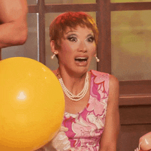 a woman in a pink dress is holding a yellow ball