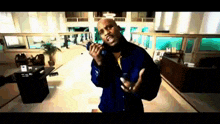 a man in a blue jacket is singing into a microphone in a room .