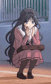 a girl in a school uniform is kneeling down with her hands on her face