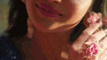 a close up of a woman 's face with a pink flower on her ear