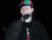 a young man wearing a hat and a black shirt that says the
