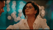 a woman wearing glasses and earrings looks at a man